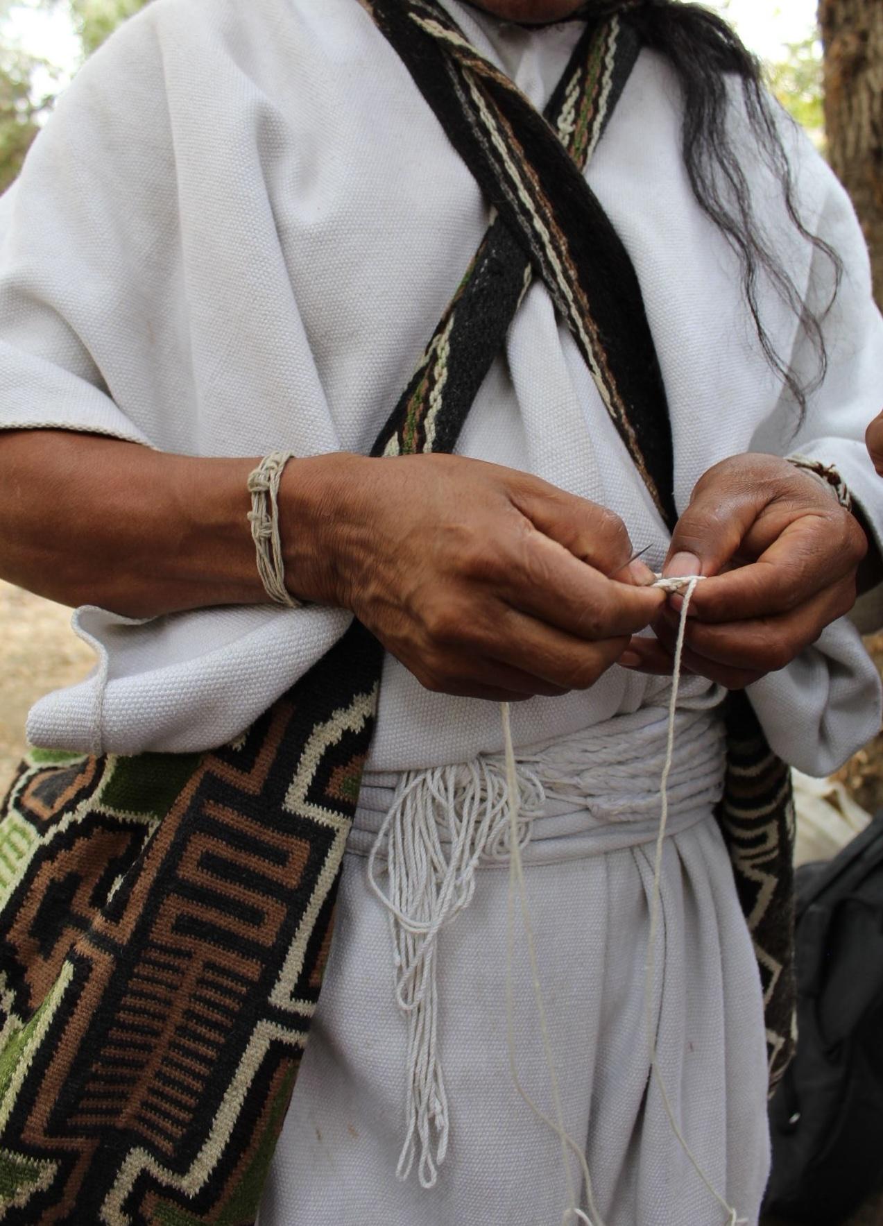 Mamo Lorenzo, an Arhuaco elder, working thread by hand in traditional white dress