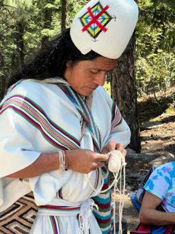 Mamo Lorenzo, an Arhuaco elder, working woven thread by hand in traditional white dress
